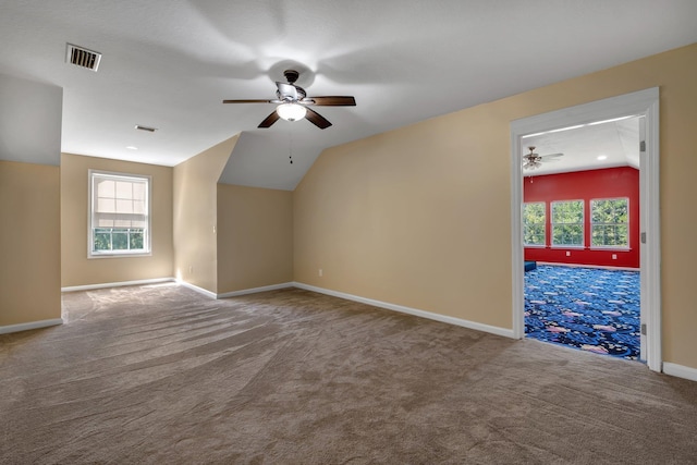 additional living space with carpet floors, plenty of natural light, visible vents, and vaulted ceiling