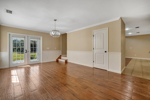 spare room featuring french doors, wainscoting, wood finished floors, and visible vents