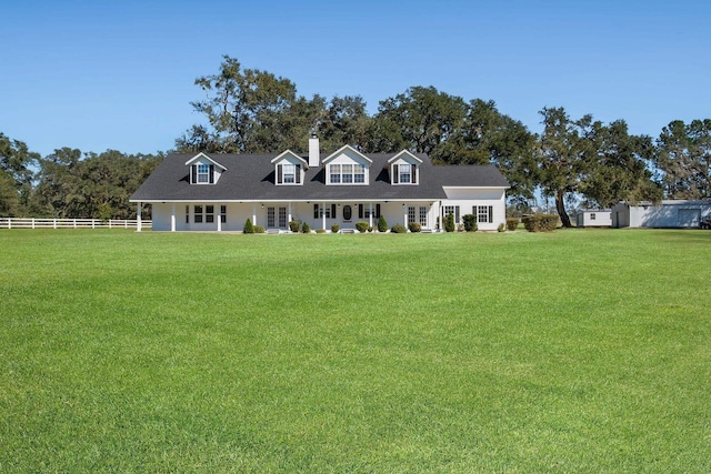 cape cod-style house featuring a chimney, fence, and a front lawn