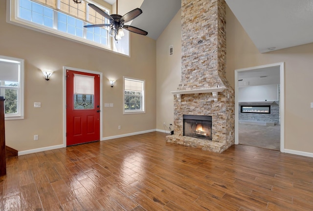 unfurnished living room featuring a ceiling fan, a fireplace, baseboards, and wood finished floors