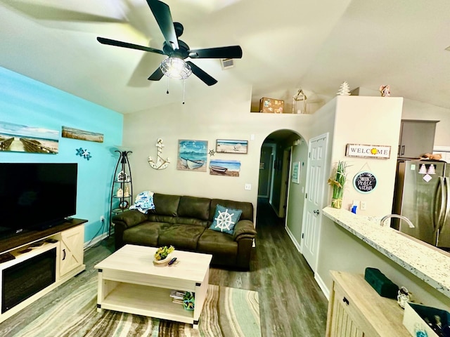 living room featuring dark hardwood / wood-style flooring, ceiling fan, and vaulted ceiling