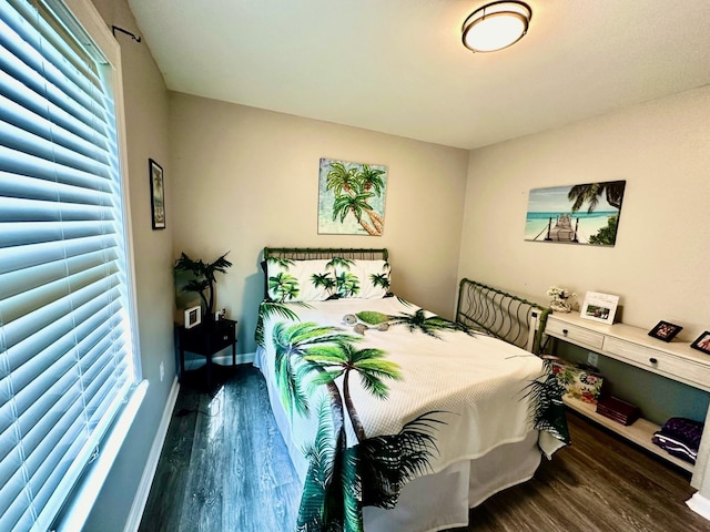 bedroom with multiple windows and dark hardwood / wood-style floors