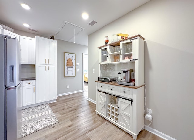 2825 Turkey Hill Trl, Tallahassee, FL 32312 - kitchen featuring stainless steel fridge, visible vents, light wood finished floors, and white cabinetry