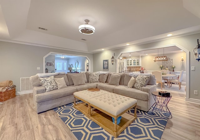 2825 Turkey Hill Trl, Tallahassee, FL 32312 - living room with arched walkways, a tray ceiling, visible vents, and light wood-type flooring