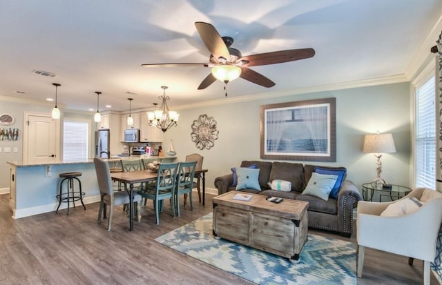 living room featuring wood-type flooring, ceiling fan with notable chandelier, and ornamental molding