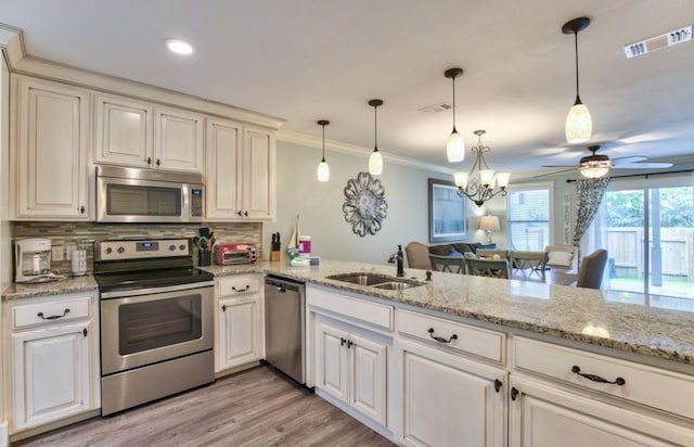 kitchen featuring kitchen peninsula, appliances with stainless steel finishes, sink, and hanging light fixtures