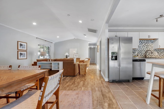 dining area with sink, vaulted ceiling, ornamental molding, and light wood-type flooring