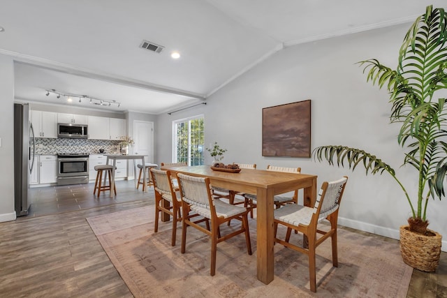 dining room featuring crown molding, lofted ceiling, and dark wood-type flooring