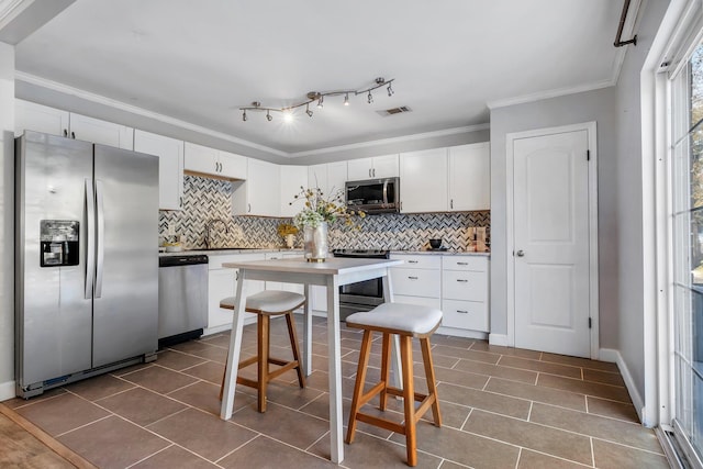 kitchen with backsplash, stainless steel appliances, and white cabinets