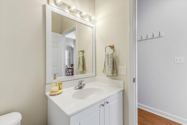 bathroom featuring toilet, wood finished floors, vanity, and baseboards