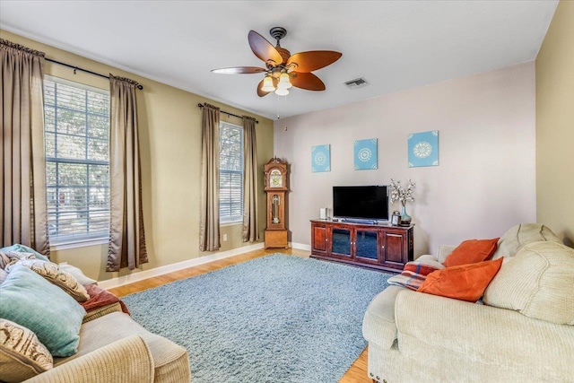 living room featuring a healthy amount of sunlight, light wood finished floors, visible vents, and a ceiling fan