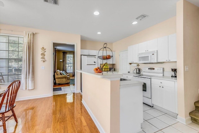 kitchen with white cabinets, white appliances, visible vents, and light countertops