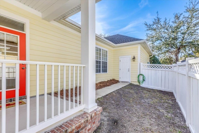 doorway to property with a shingled roof and fence