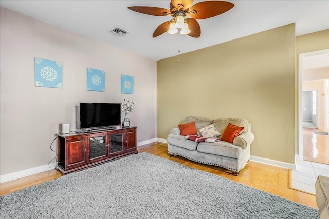 living area with wood finished floors, visible vents, and baseboards