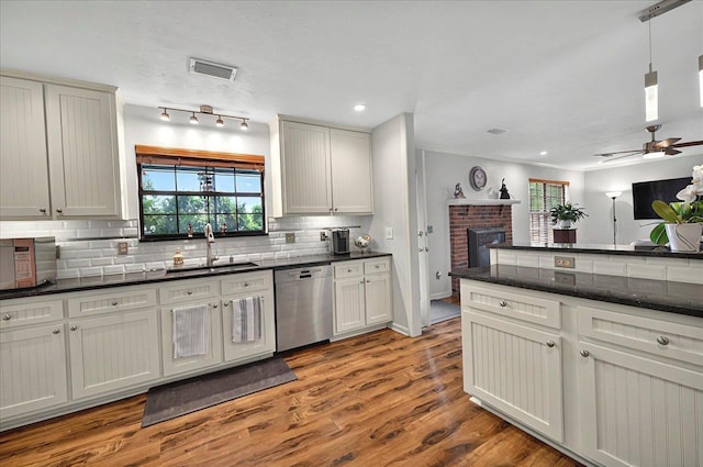 kitchen with stainless steel dishwasher, a sink, tasteful backsplash, visible vents, and ceiling fan