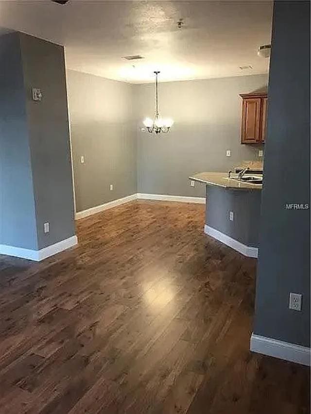 unfurnished dining area featuring dark hardwood / wood-style floors and an inviting chandelier