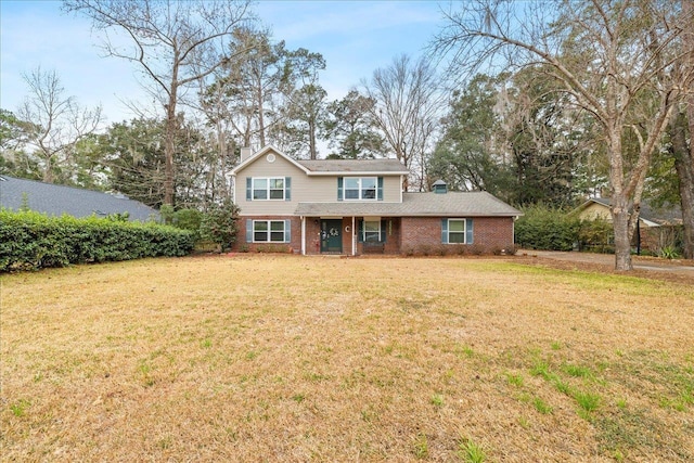 traditional home featuring brick siding, a chimney, and a front yard