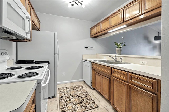kitchen featuring white appliances, light tile patterned floors, light countertops, brown cabinets, and a sink