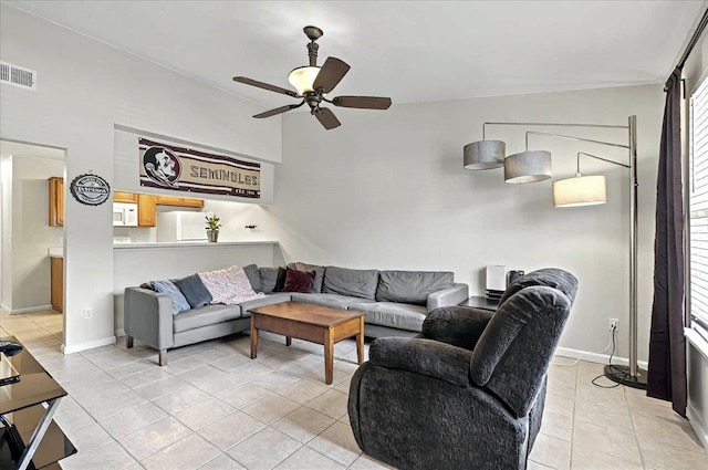 living area featuring ceiling fan, baseboards, visible vents, light tile patterned flooring, and a towering ceiling