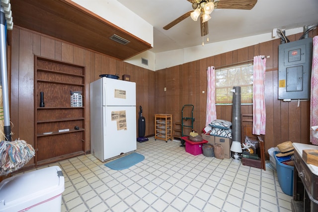 kitchen with electric panel, wood walls, ceiling fan, and white fridge