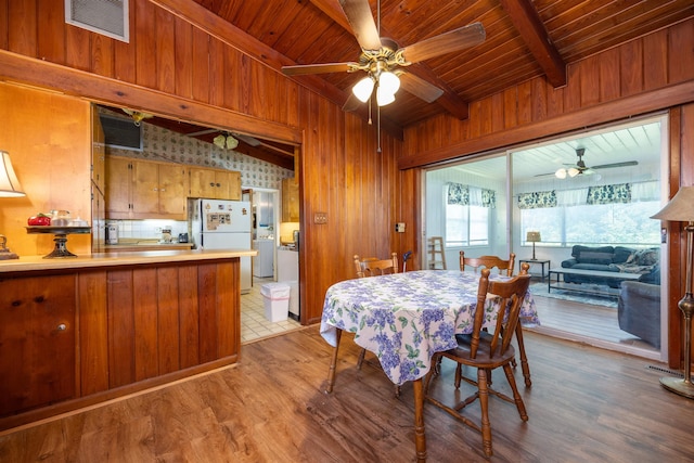 dining area with lofted ceiling with beams, wooden ceiling, light hardwood / wood-style floors, and wood walls