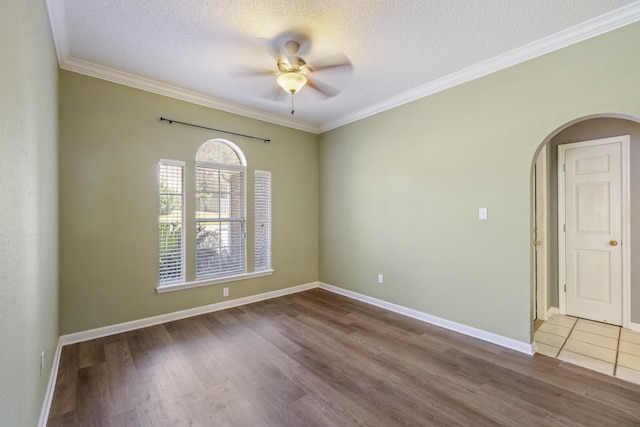 spare room with arched walkways, ornamental molding, a textured ceiling, and wood finished floors