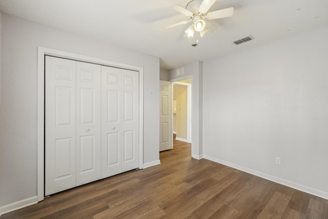 unfurnished bedroom featuring a closet, dark wood finished floors, visible vents, and baseboards