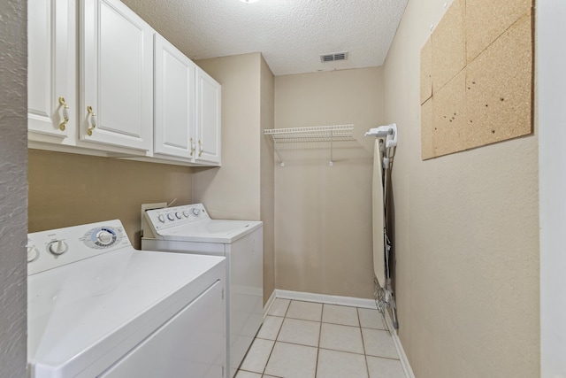 laundry area with light tile patterned floors, visible vents, cabinet space, a textured ceiling, and washer and dryer