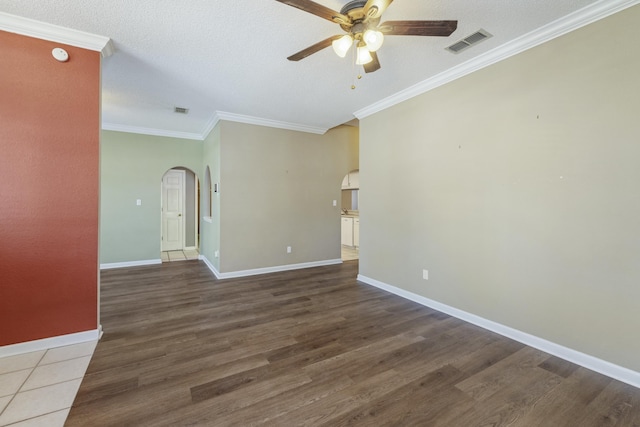 unfurnished room featuring arched walkways, wood finished floors, and visible vents