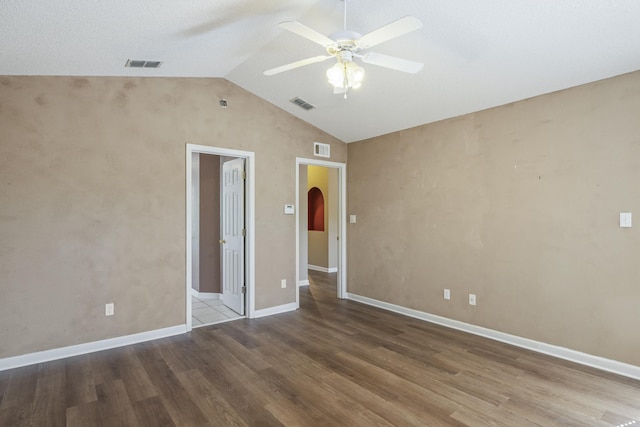 spare room with ceiling fan, visible vents, arched walkways, and wood finished floors