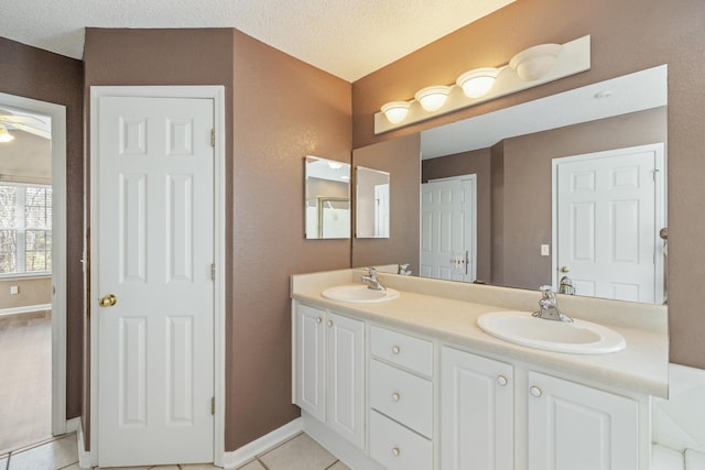 bathroom with tile patterned floors, a sink, a textured ceiling, and double vanity