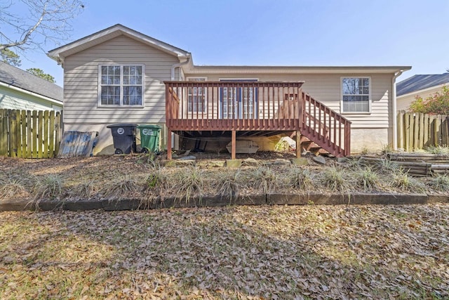 rear view of house with fence, a wooden deck, and stairs