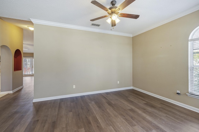 empty room featuring ornamental molding, arched walkways, visible vents, and dark wood-style floors