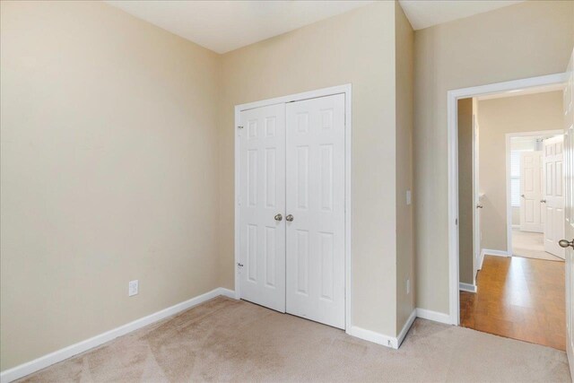 unfurnished bedroom featuring light carpet and a closet