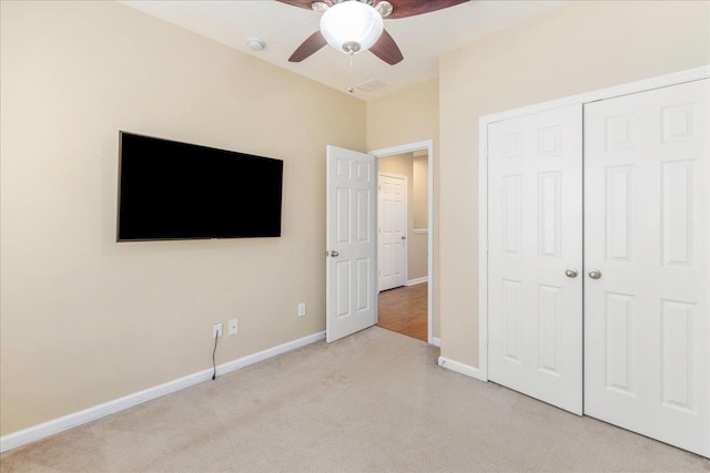 unfurnished bedroom with ceiling fan, light colored carpet, and a closet