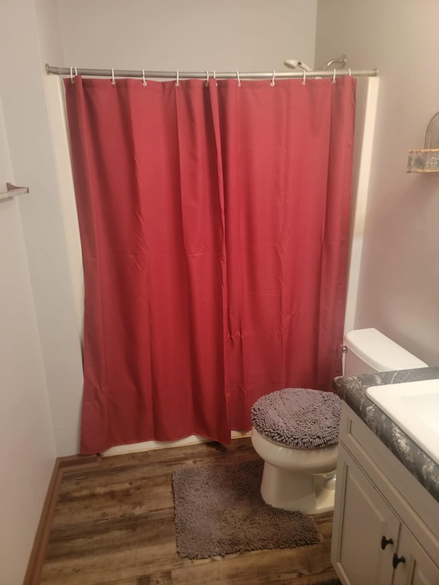 bathroom featuring walk in shower, vanity, hardwood / wood-style flooring, and toilet