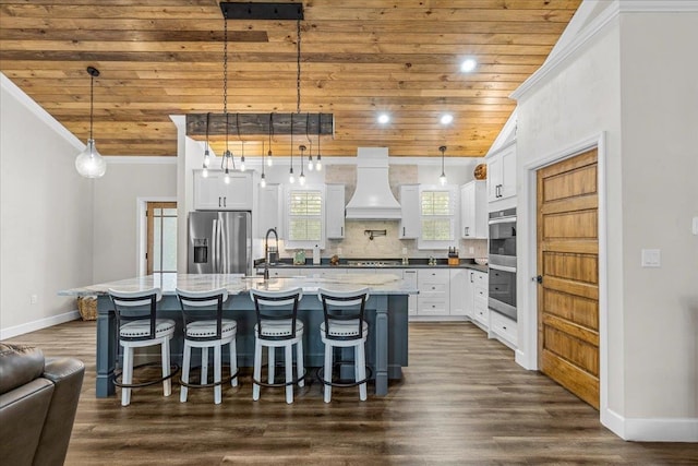 kitchen featuring an island with sink, premium range hood, hanging light fixtures, and stainless steel appliances