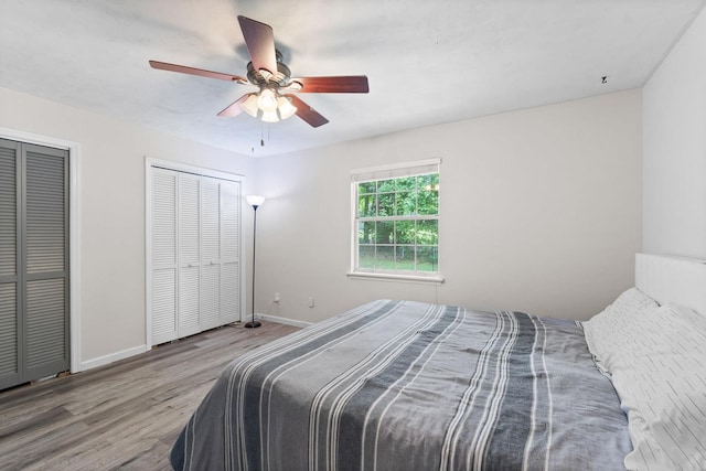 bedroom with multiple closets, ceiling fan, and light hardwood / wood-style flooring