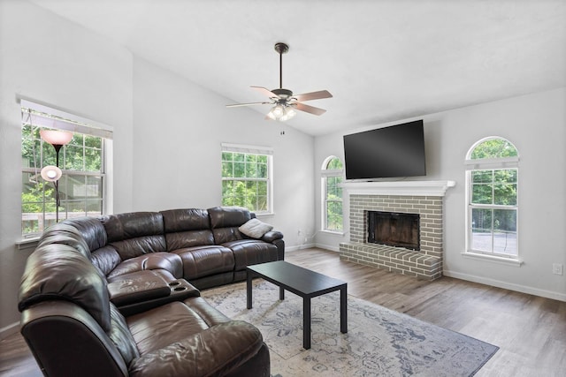 living room featuring a brick fireplace, vaulted ceiling, light hardwood / wood-style flooring, and plenty of natural light