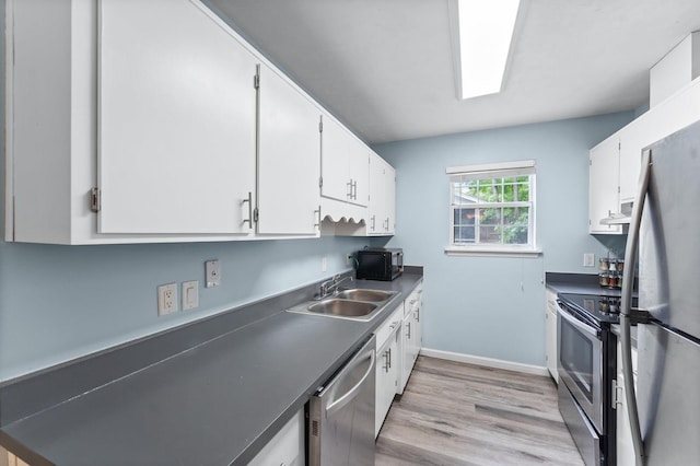 kitchen with appliances with stainless steel finishes, light wood-type flooring, white cabinetry, and sink