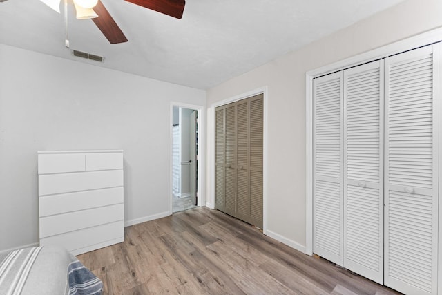 unfurnished bedroom featuring light wood-type flooring, two closets, and ceiling fan