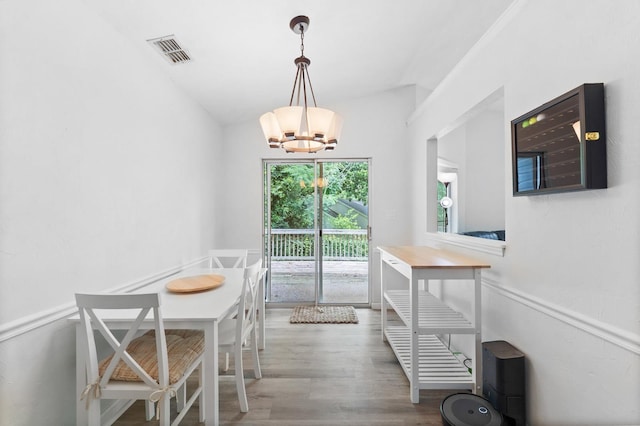 dining room with hardwood / wood-style floors, lofted ceiling, and a chandelier