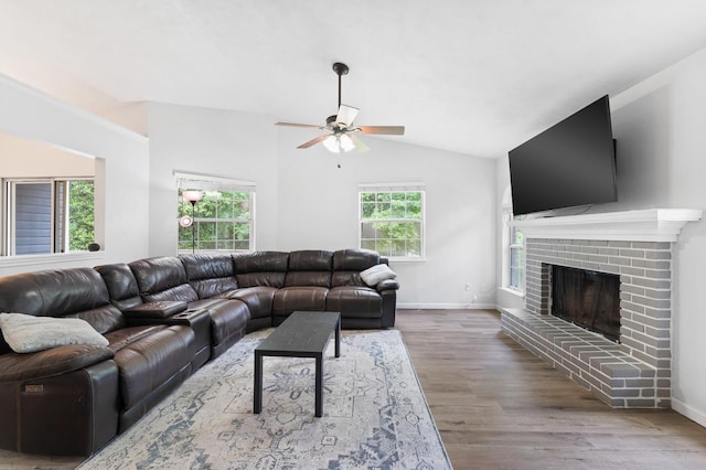 living room featuring a brick fireplace, a healthy amount of sunlight, lofted ceiling, and hardwood / wood-style flooring