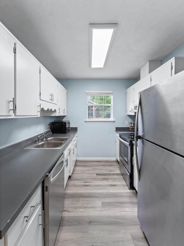 kitchen with light hardwood / wood-style floors, white cabinetry, sink, and appliances with stainless steel finishes