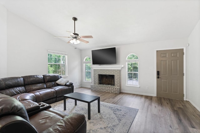 living room featuring ceiling fan, hardwood / wood-style floors, vaulted ceiling, and a brick fireplace