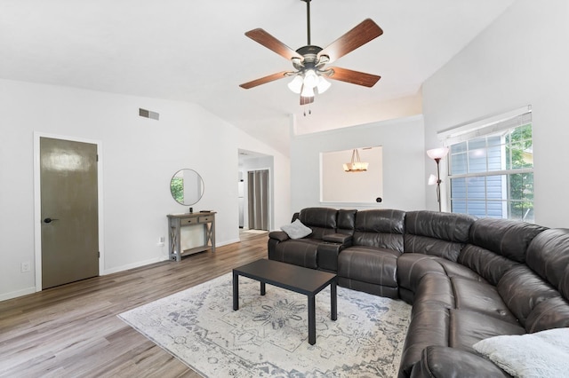 living room featuring ceiling fan with notable chandelier, light wood-type flooring, and vaulted ceiling