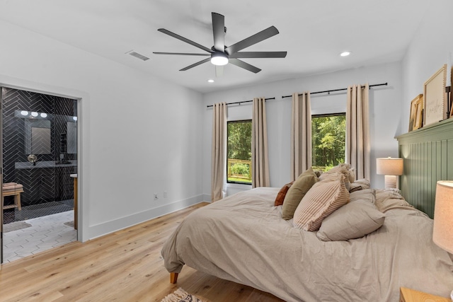 bedroom with light hardwood / wood-style flooring, ensuite bath, and ceiling fan