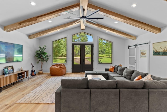 living room featuring light wood-type flooring, lofted ceiling with beams, french doors, and a barn door