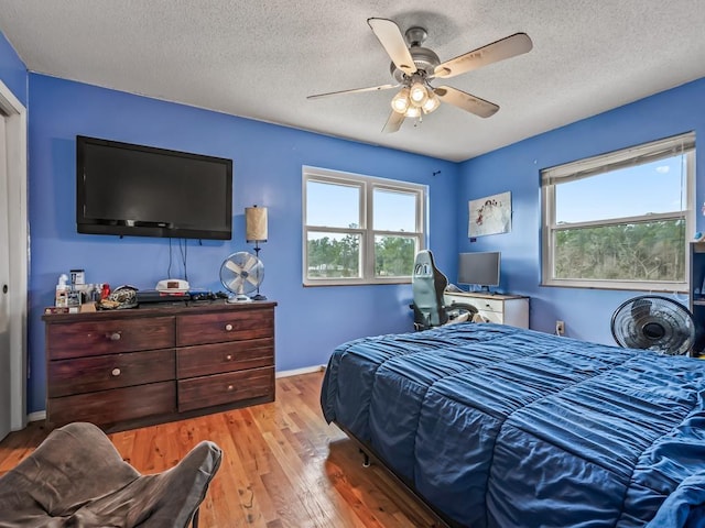 bedroom with a textured ceiling, light hardwood / wood-style flooring, and ceiling fan