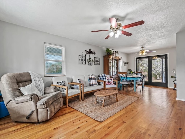 living room featuring ceiling fan, wood-type flooring, and a textured ceiling